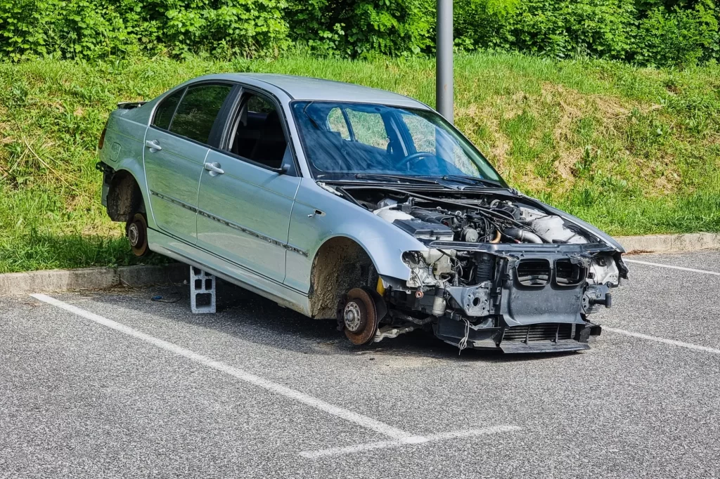 Vandalizované auto stojí na cihlách s odstraněnými koly a předními částmi motoru