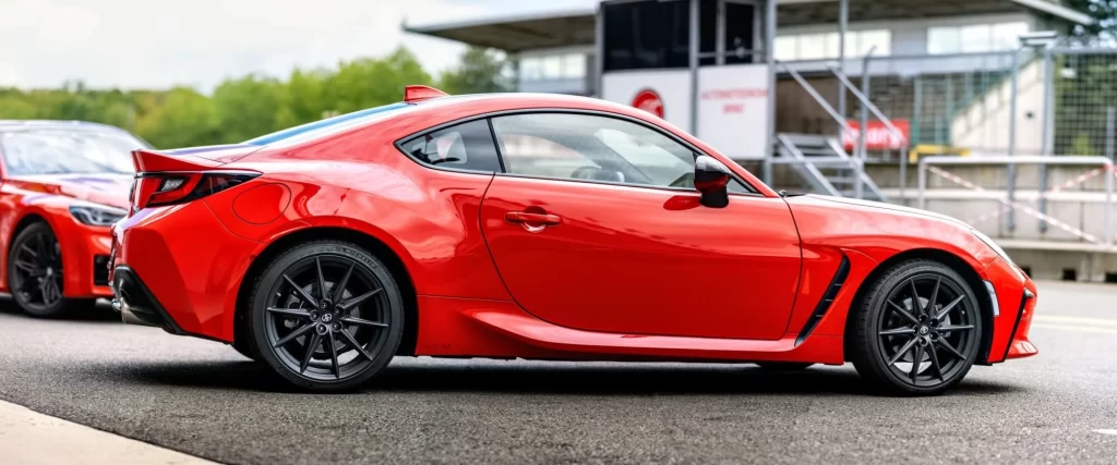 Japonský červený sportovní vůz Toyota GR86 zaparkovaný venku před závodním okruhem v Brně
