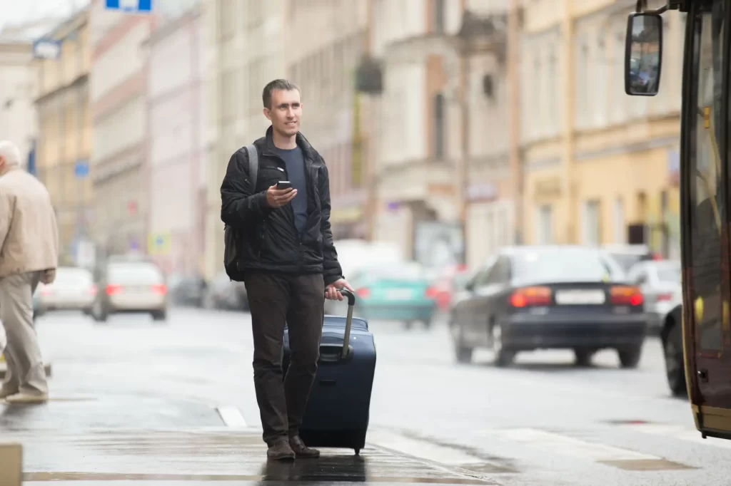 MaaS zjednoduší cestování - MotorGuru.cz Muž s kufrem na zastávce