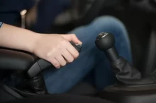 Ruka řidiče, která zatahuje mechanickou ruční brzdu