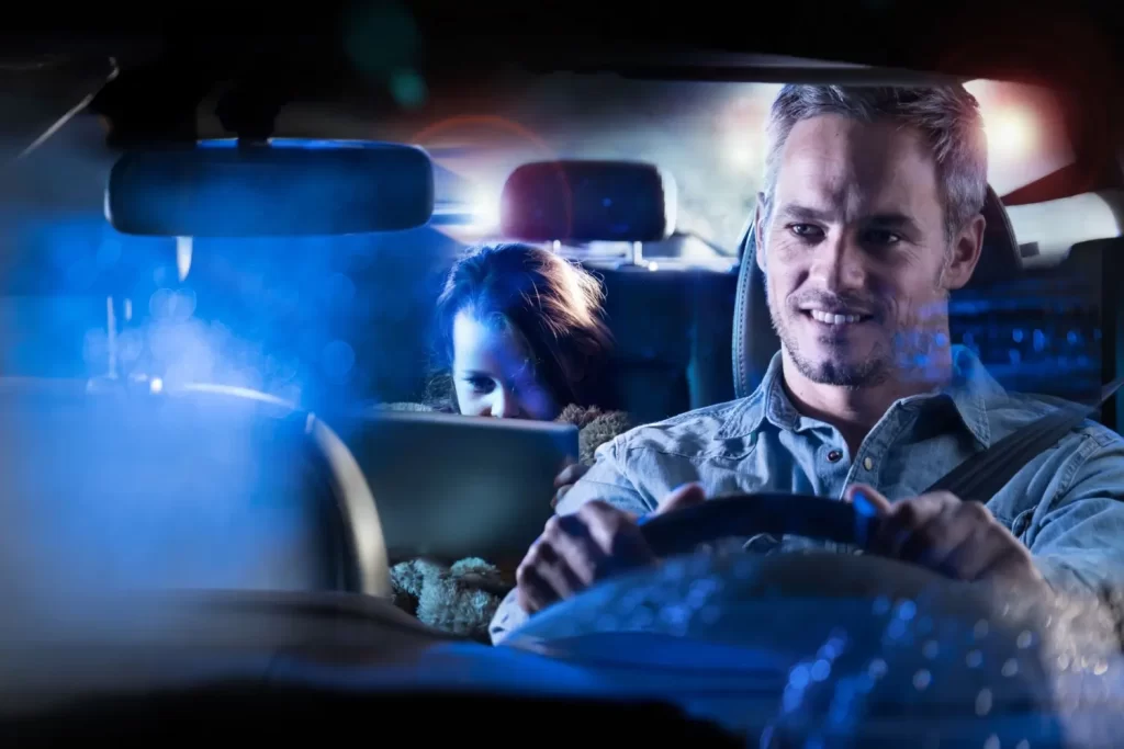 - MotorGuru.cz Muž řídí auto v noci, zatímco dítě vzadu si hraje s tabletem