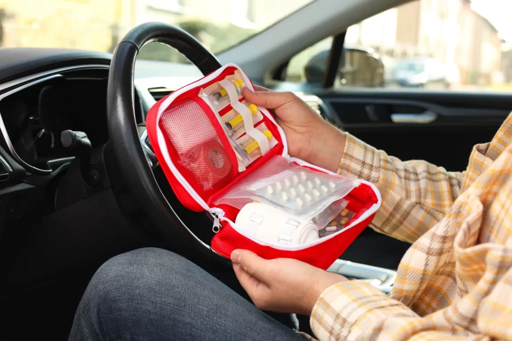 - MotorGuru.cz Muž sedí v autě a drží otevřenou autolékárničku
