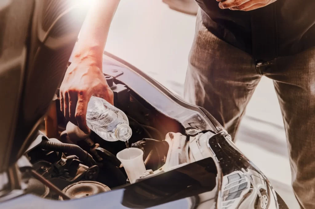 - MotorGuru.cz Muž nalévá vodu do nádržky na chladící kapalinu.