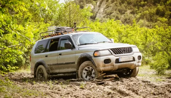 Šedé SUV zapadlé v hlubokém bahně na venkovské cestě