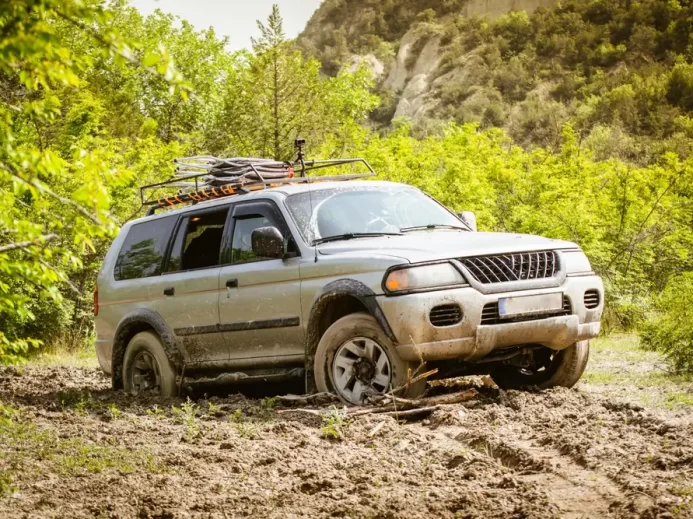 Šedé SUV zapadlé v hlubokém bahně na venkovské cestě