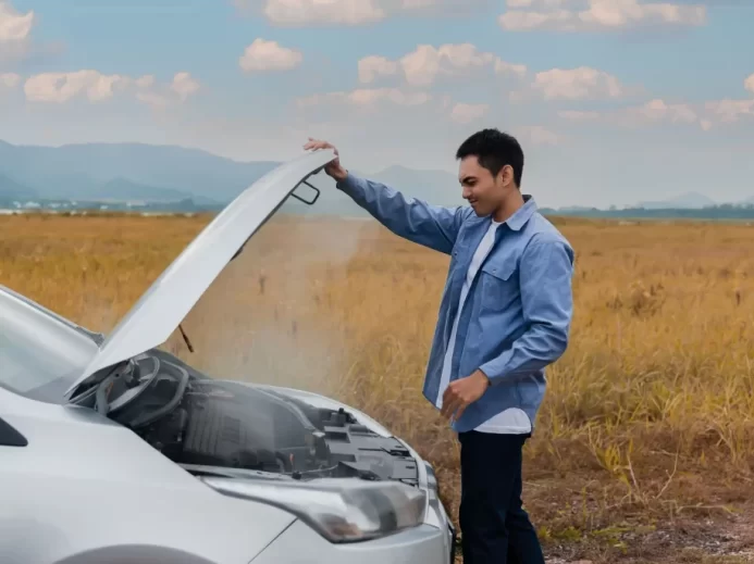 Muž stojí před autem s otevřenou kapotou