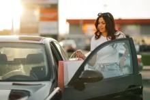 Mladá žena ukládá nákupní tašky do auta na parkovišti