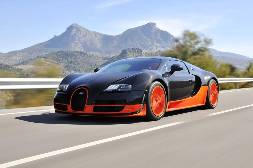 Bugatti Veyron Super Sport v černo-oranžové kombinaci během jízdy na otevřené silnici.