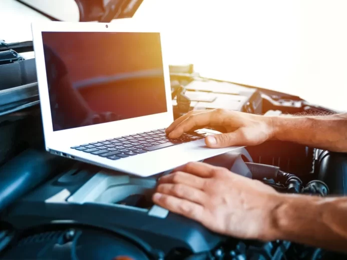 Muž provádí diagnostiku auta s notebookem