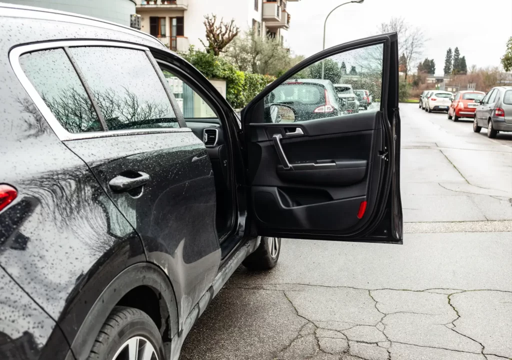 Auto s dokořán otevřenými předními dveřmi směřujícími do vozovky. 