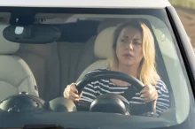 Blond žena za volantem kontroluje, zda má na silnici volno.