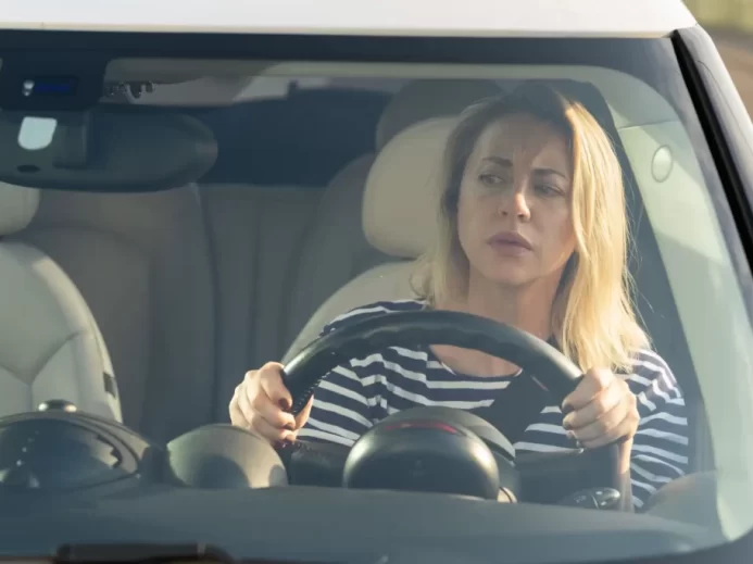 Blond žena za volantem kontroluje, zda má na silnici volno.