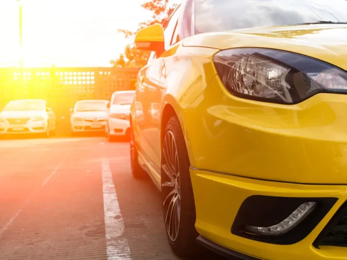 Záběr na žluté auto zaparkované na venkovním parkovišti