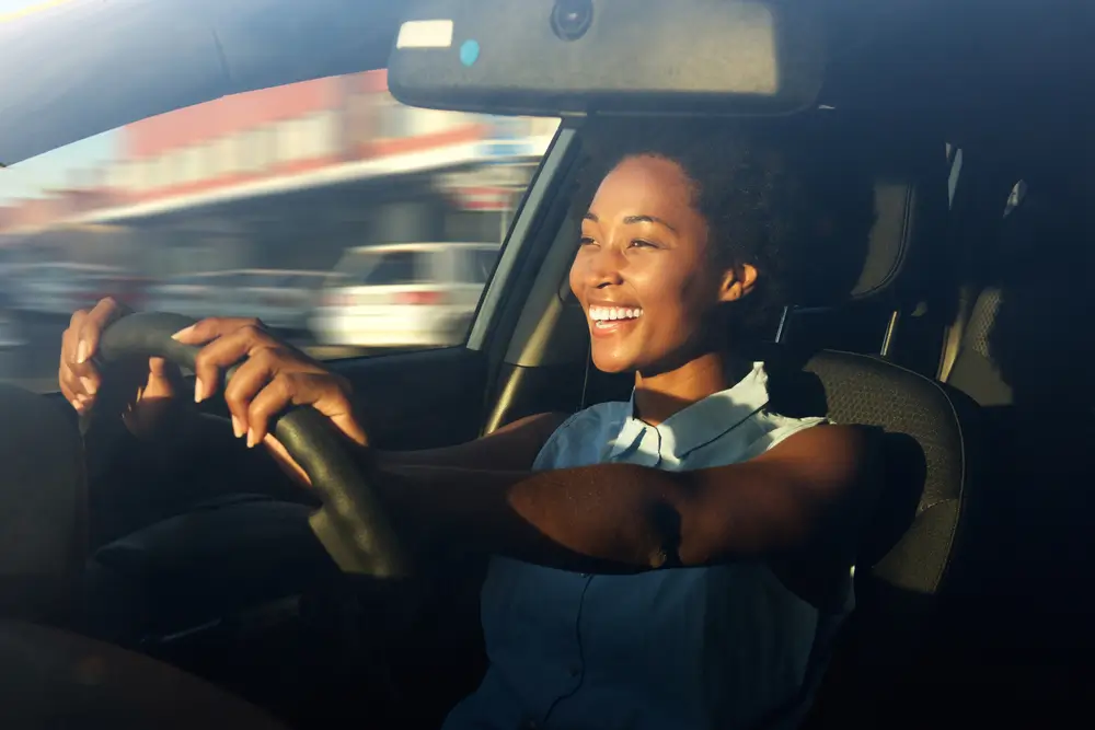 Portrét usmívající se mladé afroamerické ženy za volantem automobilu