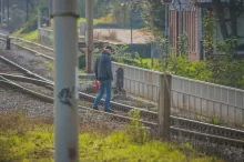 Muž přechází kolejiště když svítí červené světlo
