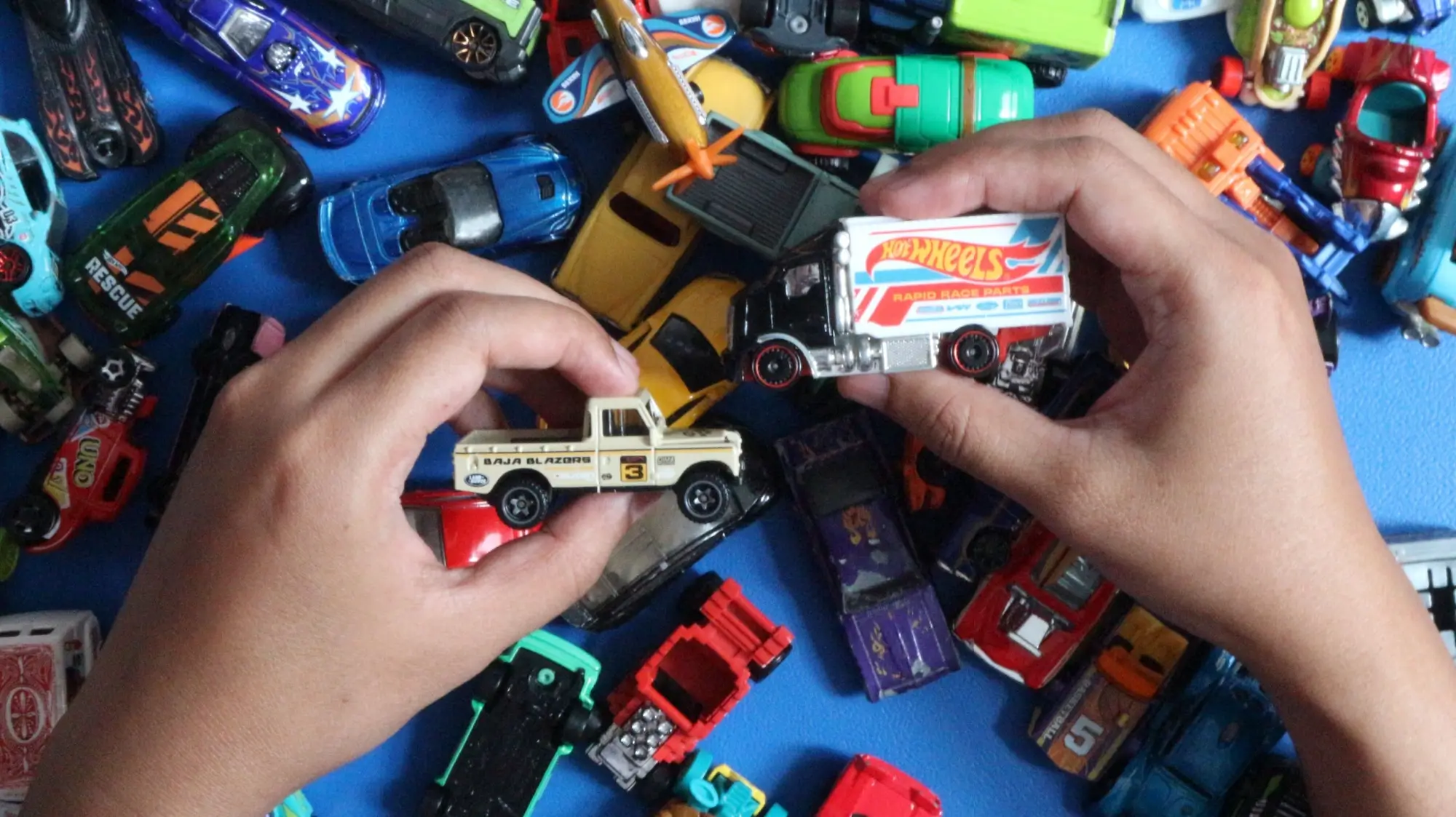 Dětské ruce hrající si s autíčky Hot Wheels.