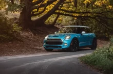 Modrý Mini Cooper zaparkovaný na lesní silnici