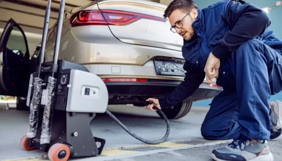 Muž měří v autoservisu emise