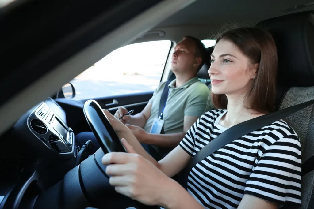 Žena sedí za volantem v autoškole a soustředěně řídí.