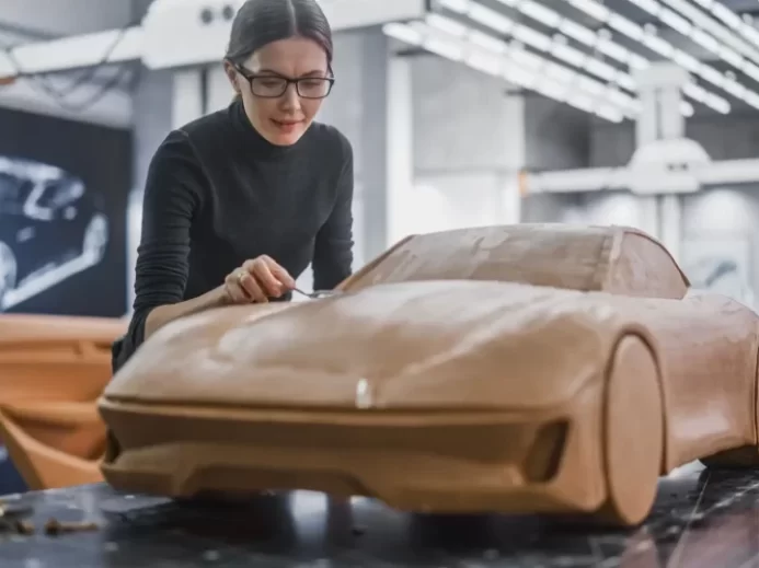 Žena pracuje v laboratoři na hliněném prototypu auta