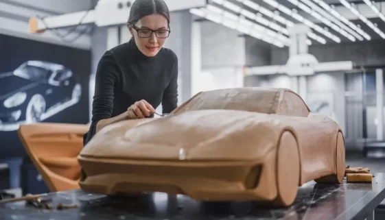 Žena pracuje v laboratoři na hliněném prototypu auta