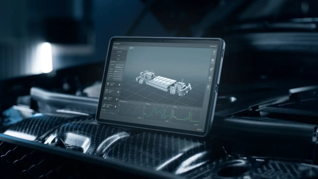 Tablet položený na karoserii vozu, který zobrazuje detailní 3D model automobilového podvozku včetně bateriových modulů