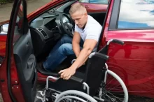 Řidič s postižením přesedá z invalidního vozíku za volant vozu přizpůsobeného jeho potřebám