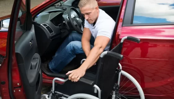 Řidič s postižením přesedá z invalidního vozíku za volant vozu přizpůsobeného jeho potřebám