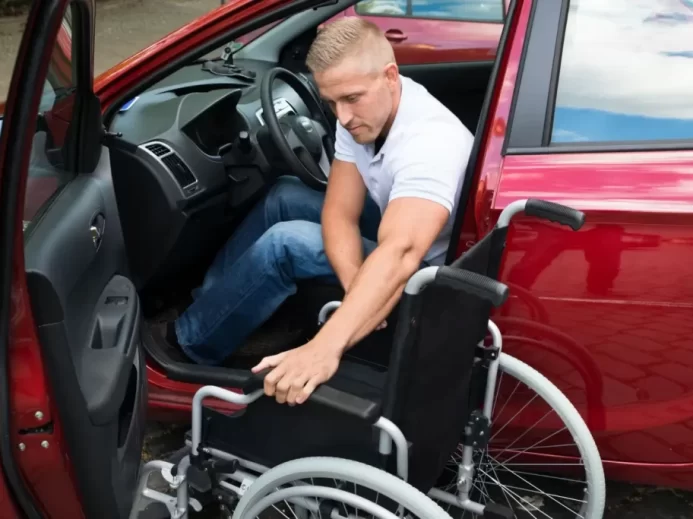 Řidič s postižením přesedá z invalidního vozíku za volant vozu přizpůsobeného jeho potřebám