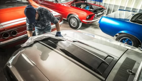 Muž v garáži leští stará americká auta