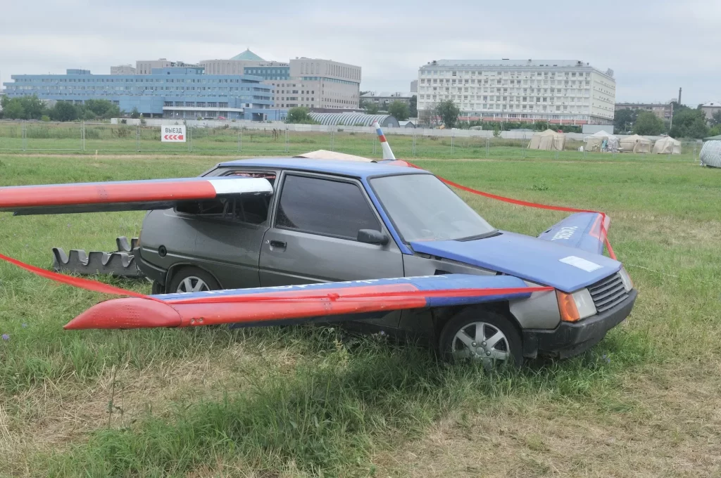 Osobní automobil, do jehož karoserie jsou ručně připevněna křídla s červeno-modrým nátěrem