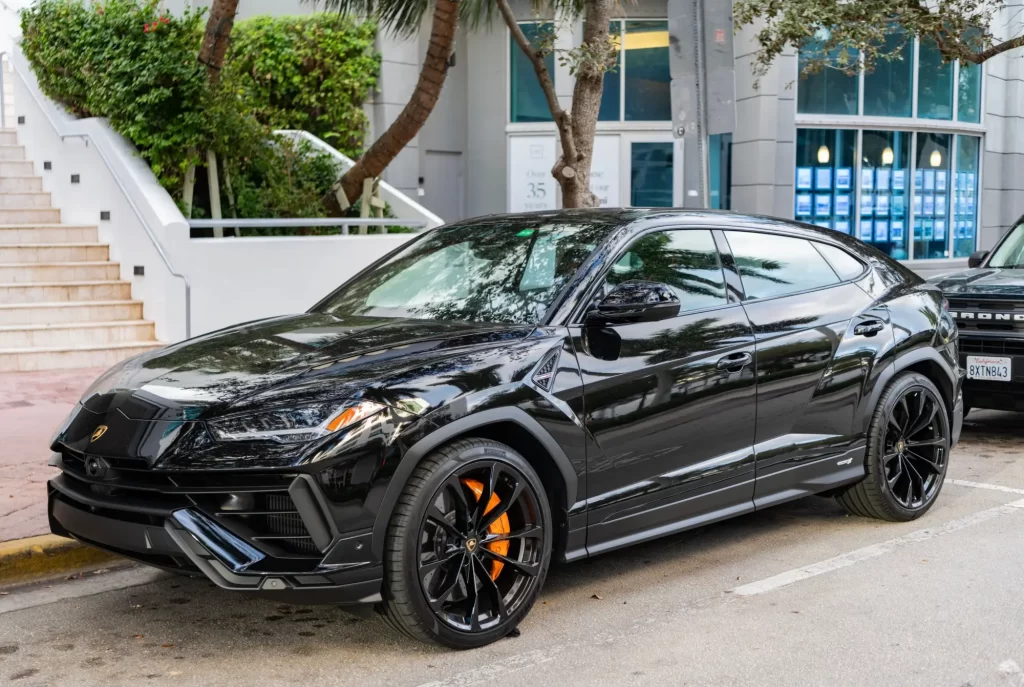 SUV automobil Lamborghini Urus zaparkovaný u chodníku v městské zástavbě. 