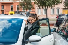 Mladá žena se naží nastoupit do auta, které je zaparkované těsně u jiného.