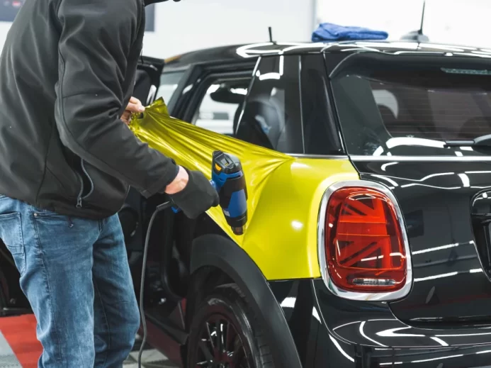 Muž dává na auto fólii