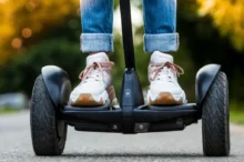 Pohled zblízka na boty jezdce stojícího na Segwayi při jízdě po asfaltu