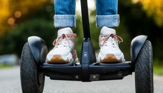Pohled zblízka na boty jezdce stojícího na Segwayi při jízdě po asfaltu