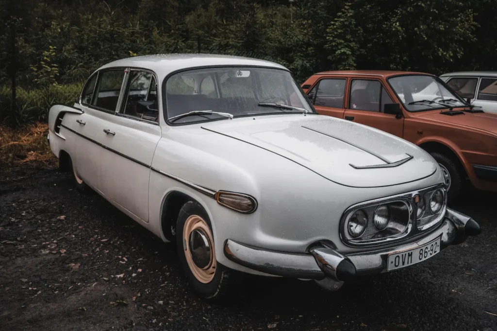 Bílá Tatra 603 zaparkovaná venku, s charakteristickou přední maskou se třemi světlomety a chromovanými nárazníky.