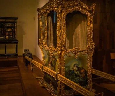 Luxusní historické nosítko s bohatou zlatou výzdobou a malovanými panely v muzeu