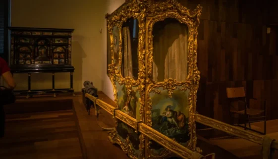 Luxusní historické nosítko s bohatou zlatou výzdobou a malovanými panely v muzeu