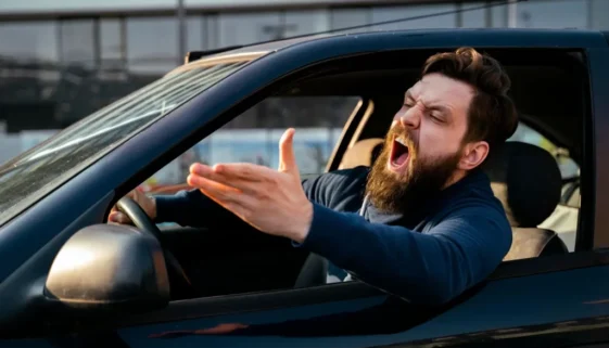 Muž s bradkou agresivně křičí z okna svého vozu