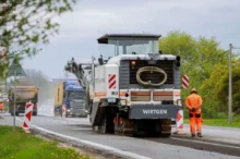 Stavba silnice, silničář stojí u asfaltovacího vozu