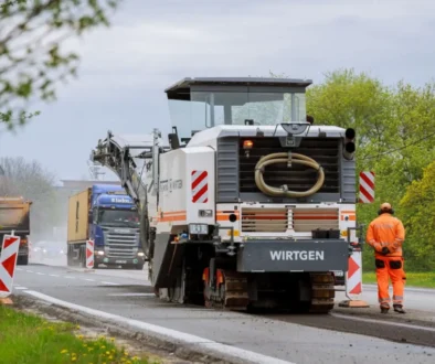 Stavba silnice, silničář stojí u asfaltovacího vozu