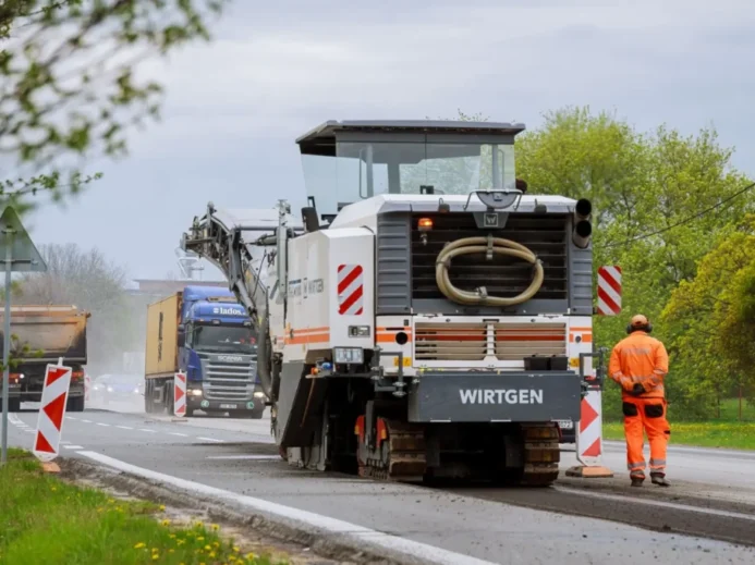 Stavba silnice, silničář stojí u asfaltovacího vozu
