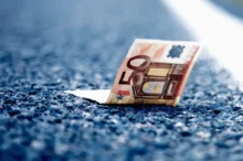 Detail padesátieurové bankovky ležící na asfaltu dálnice