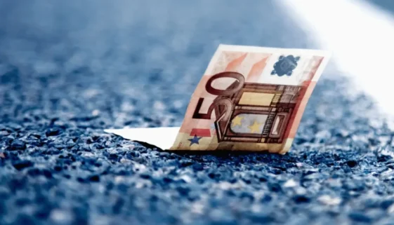 Detail padesátieurové bankovky ležící na asfaltu dálnice