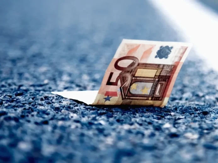 Detail padesátieurové bankovky ležící na asfaltu dálnice