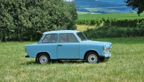 Světle modrý Trabant zaparkovaný na louce