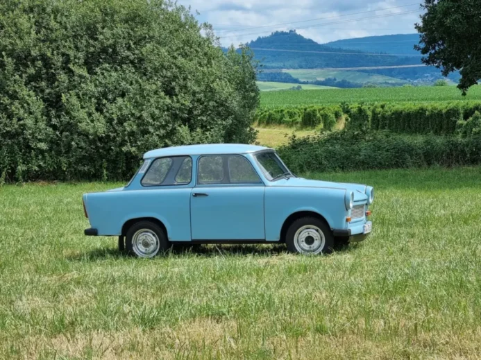 Světle modrý Trabant zaparkovaný na louce