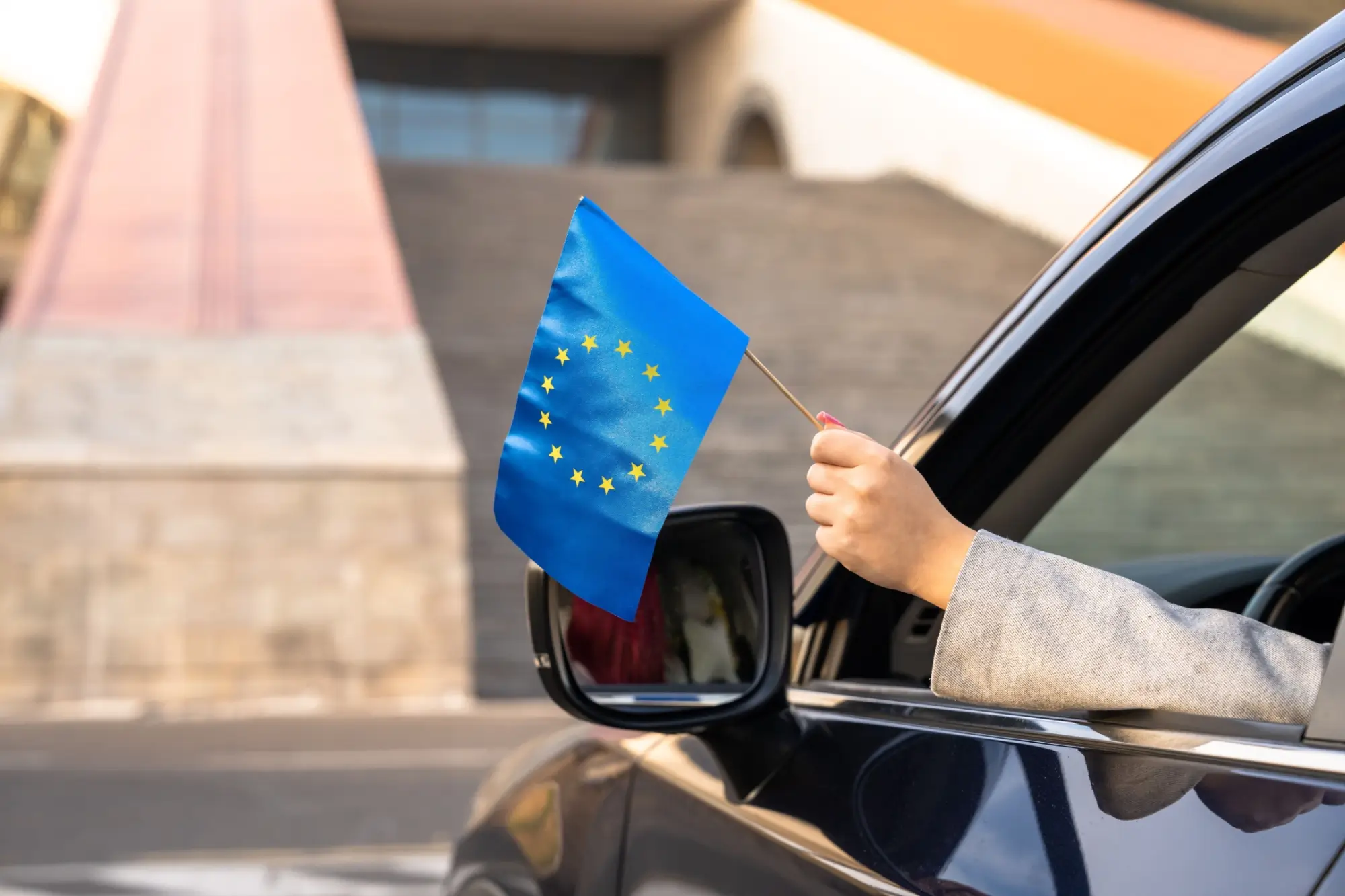 Řidič mávající vlajkou EU z auta.