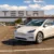 Bílá Tesla na parkovišti před firmou Tesla